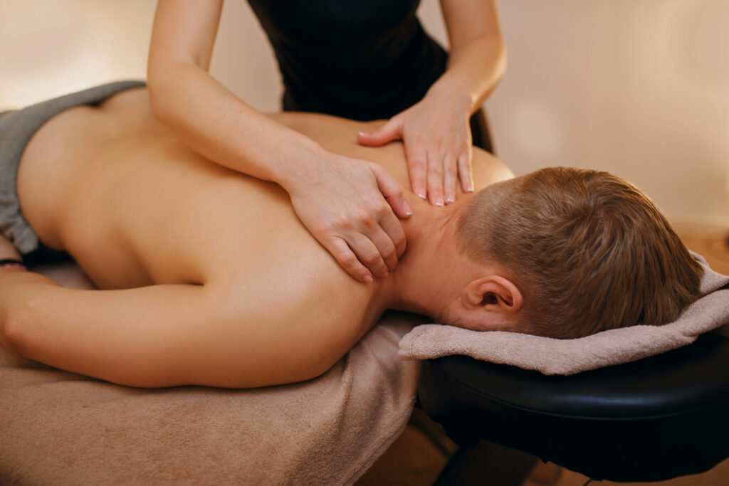 Man having shoulders massaged by female masseur
